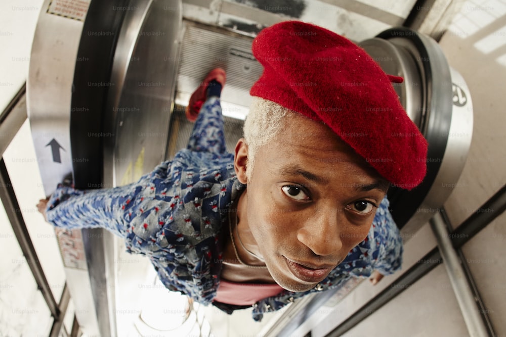 Un homme avec un chapeau rouge au sommet d’un ascenseur
