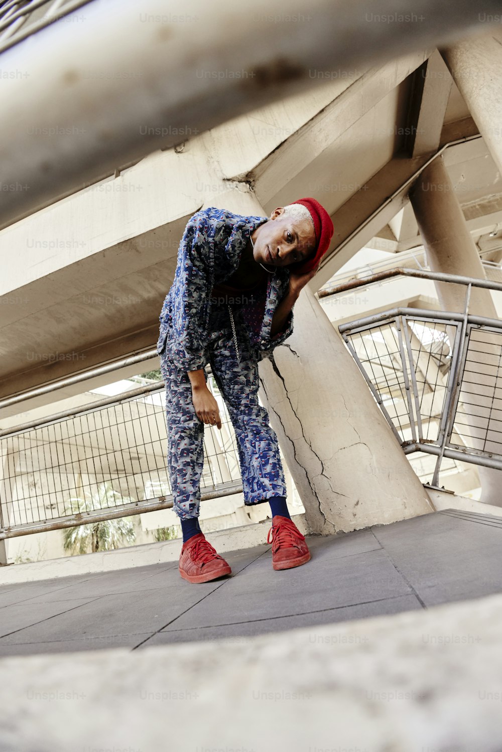 a man in blue and red is leaning against a wall