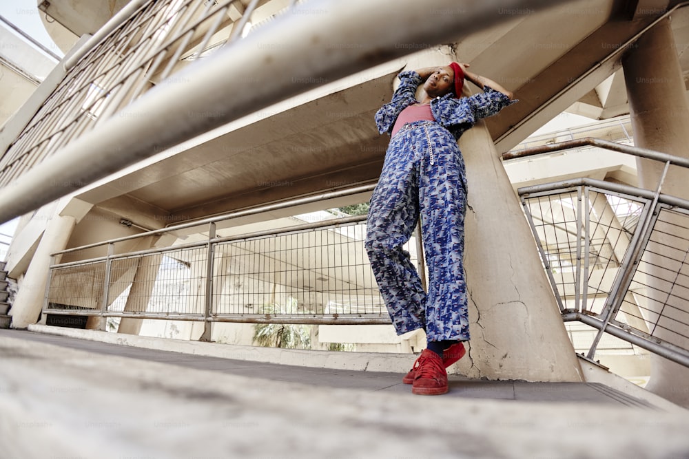 a man in a blue jumpsuit leaning against a wall