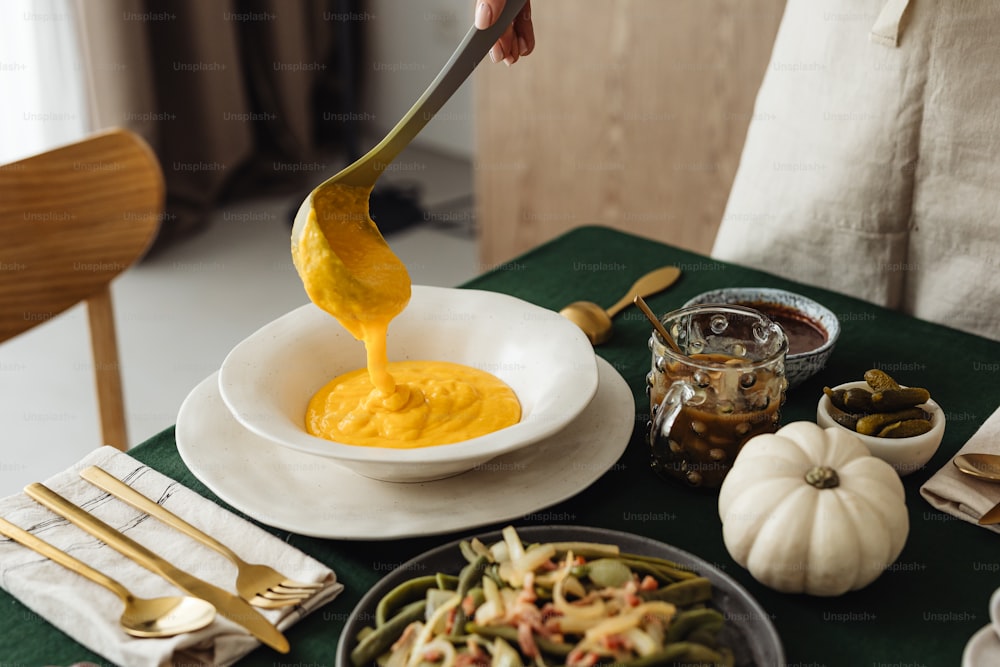 une personne versant de la moutarde dans un bol sur une table