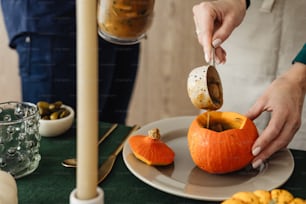a person pouring something into a pumpkin on a plate