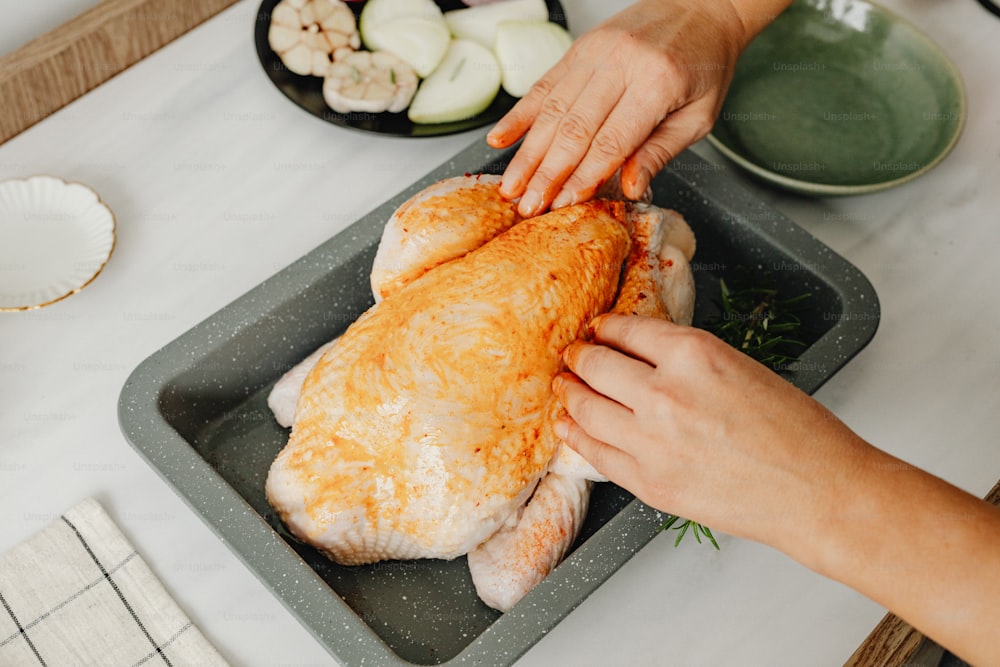 a person cutting up a piece of chicken on a tray