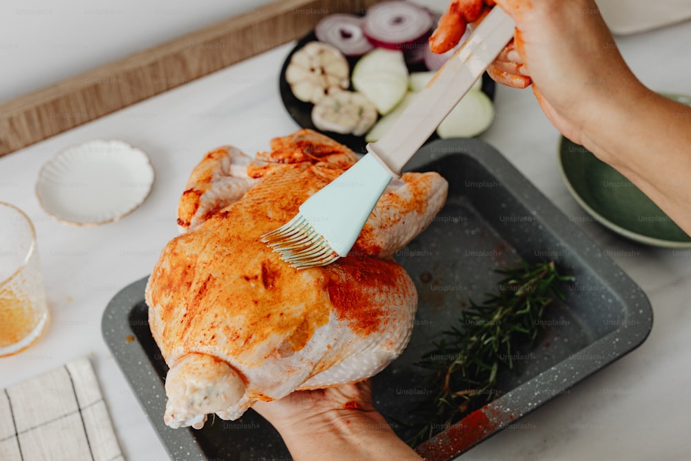 a person brushing a chicken with a brush