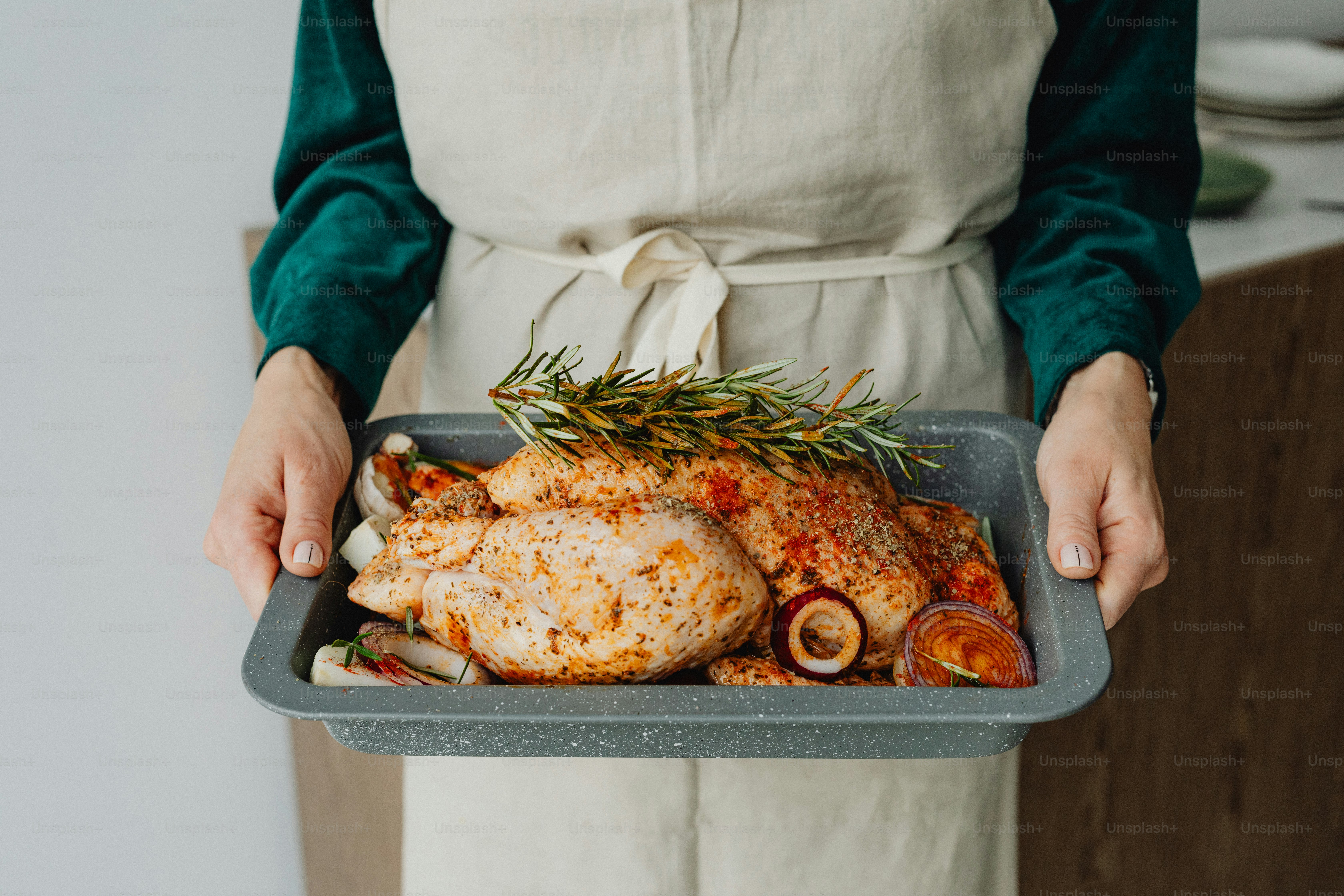 a person holding a tray with a chicken and mushrooms on it