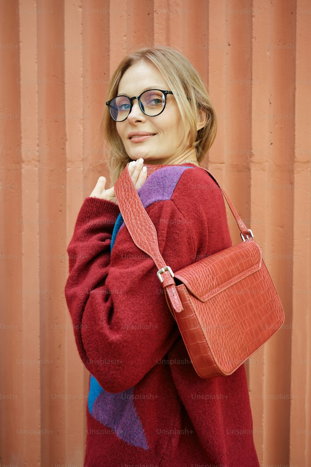 a woman wearing glasses is holding a purse