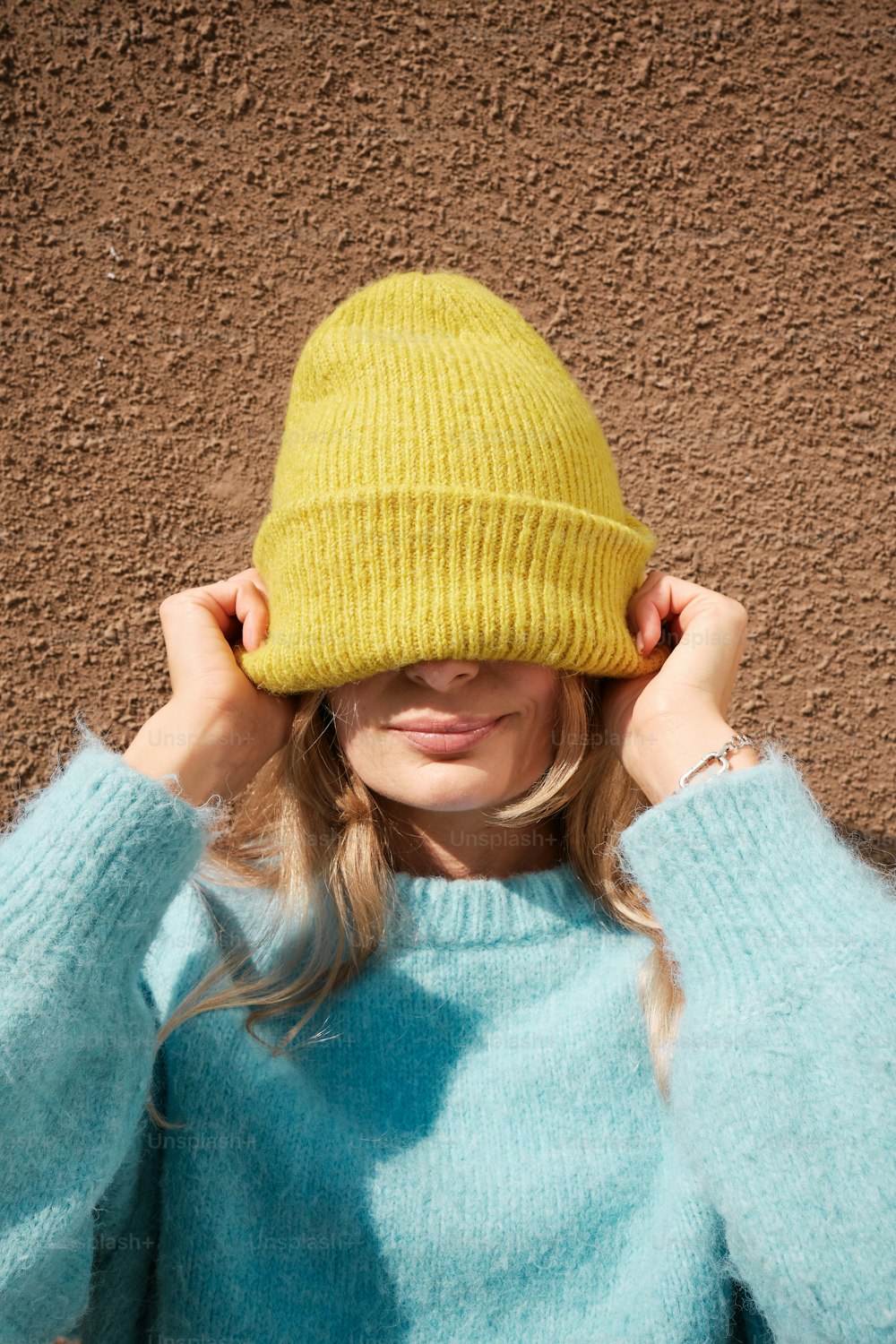a woman in a blue sweater and a yellow hat