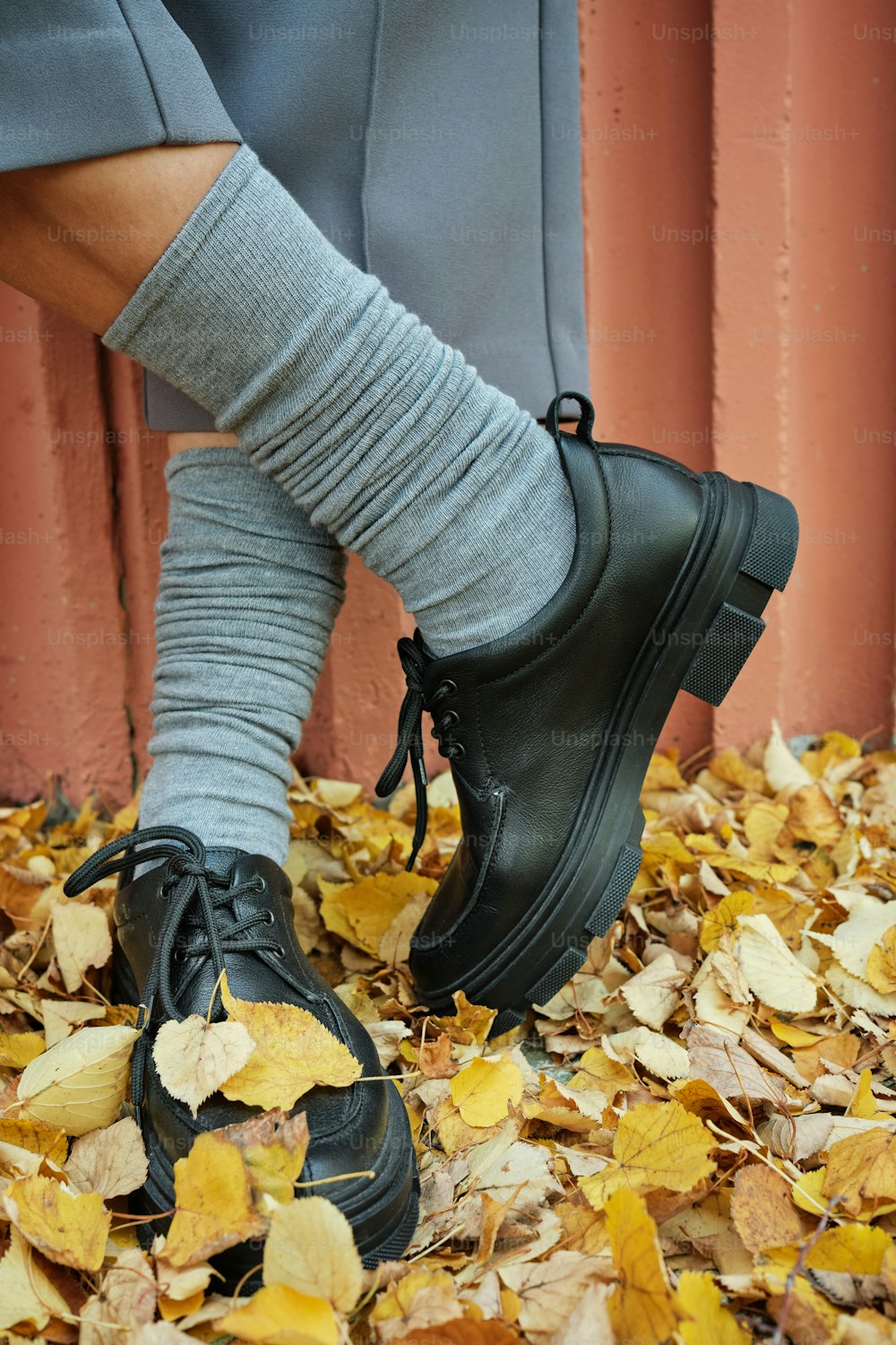 a person wearing black shoes standing on a pile of leaves