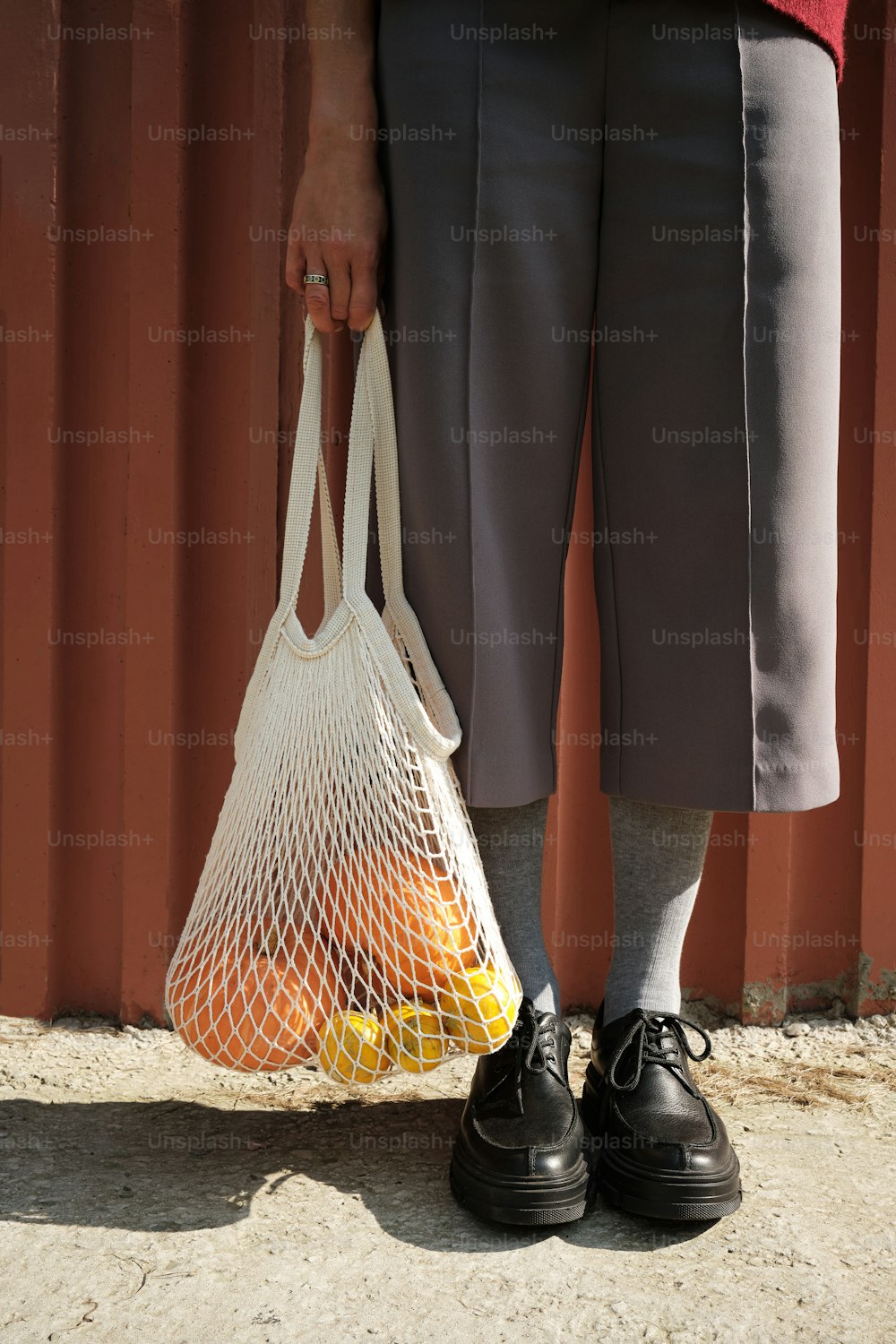a person holding a net bag with oranges in it