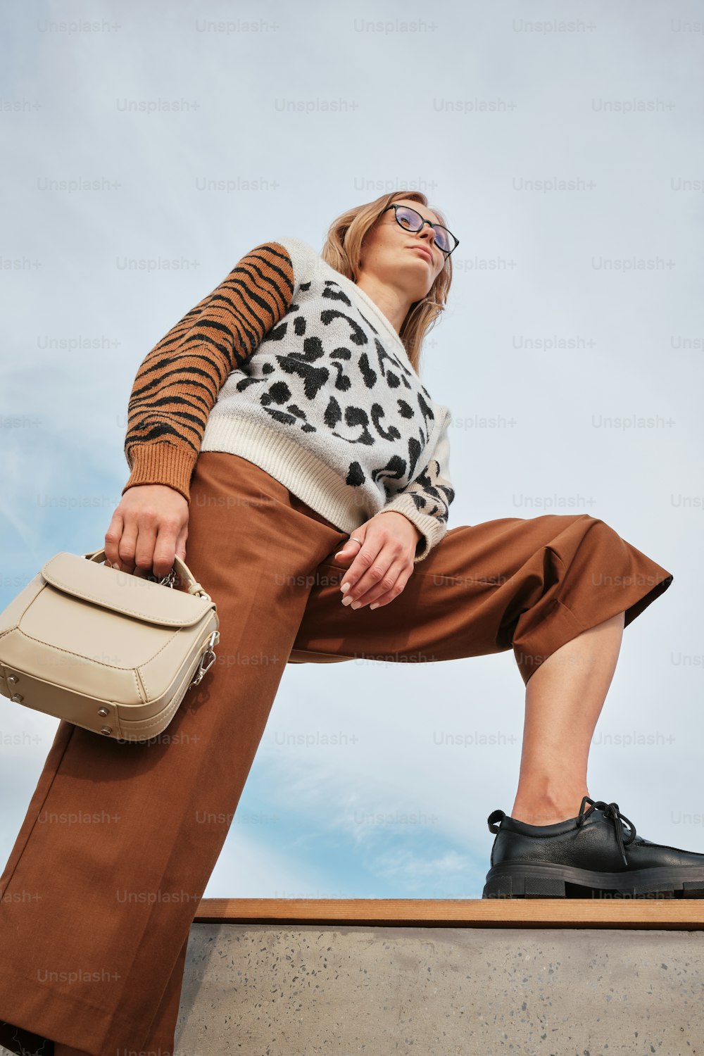 a woman sitting on a ledge holding a suitcase