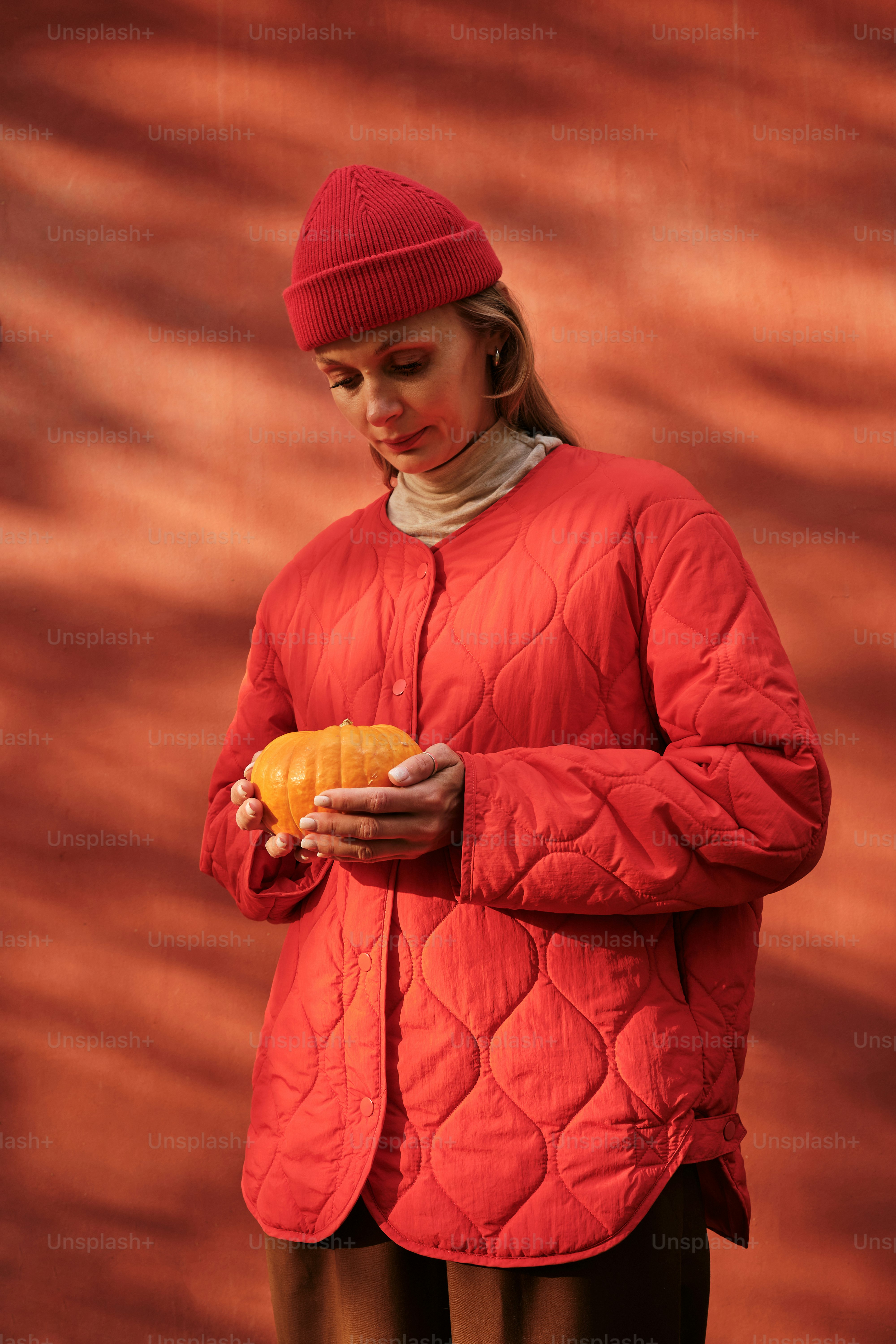 seorang wanita berjaket merah memegang oranye