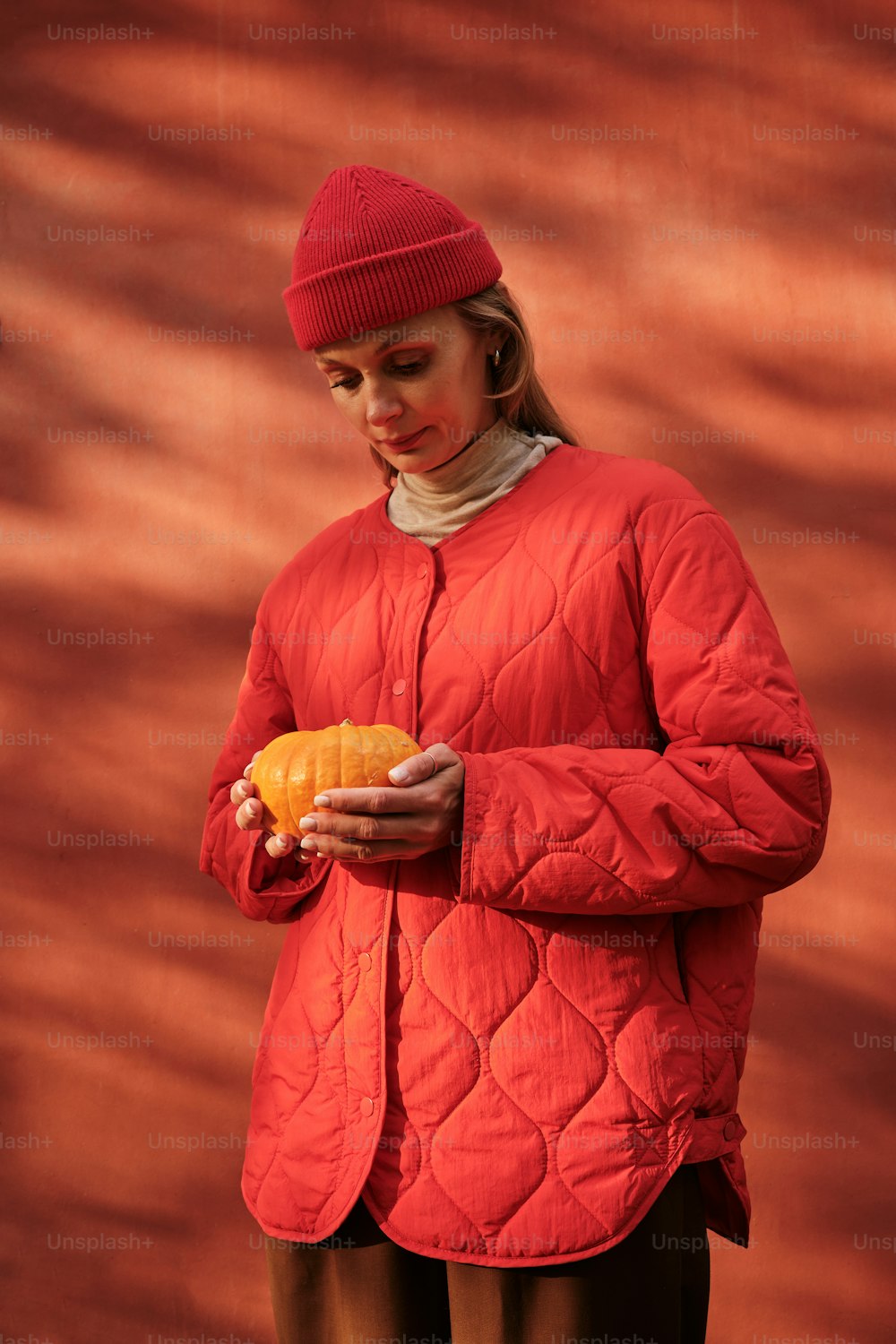 a woman in a red jacket holding an orange
