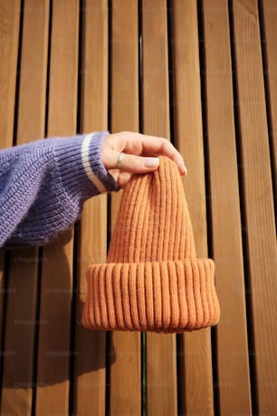 a person's hand holding a knitted orange hat