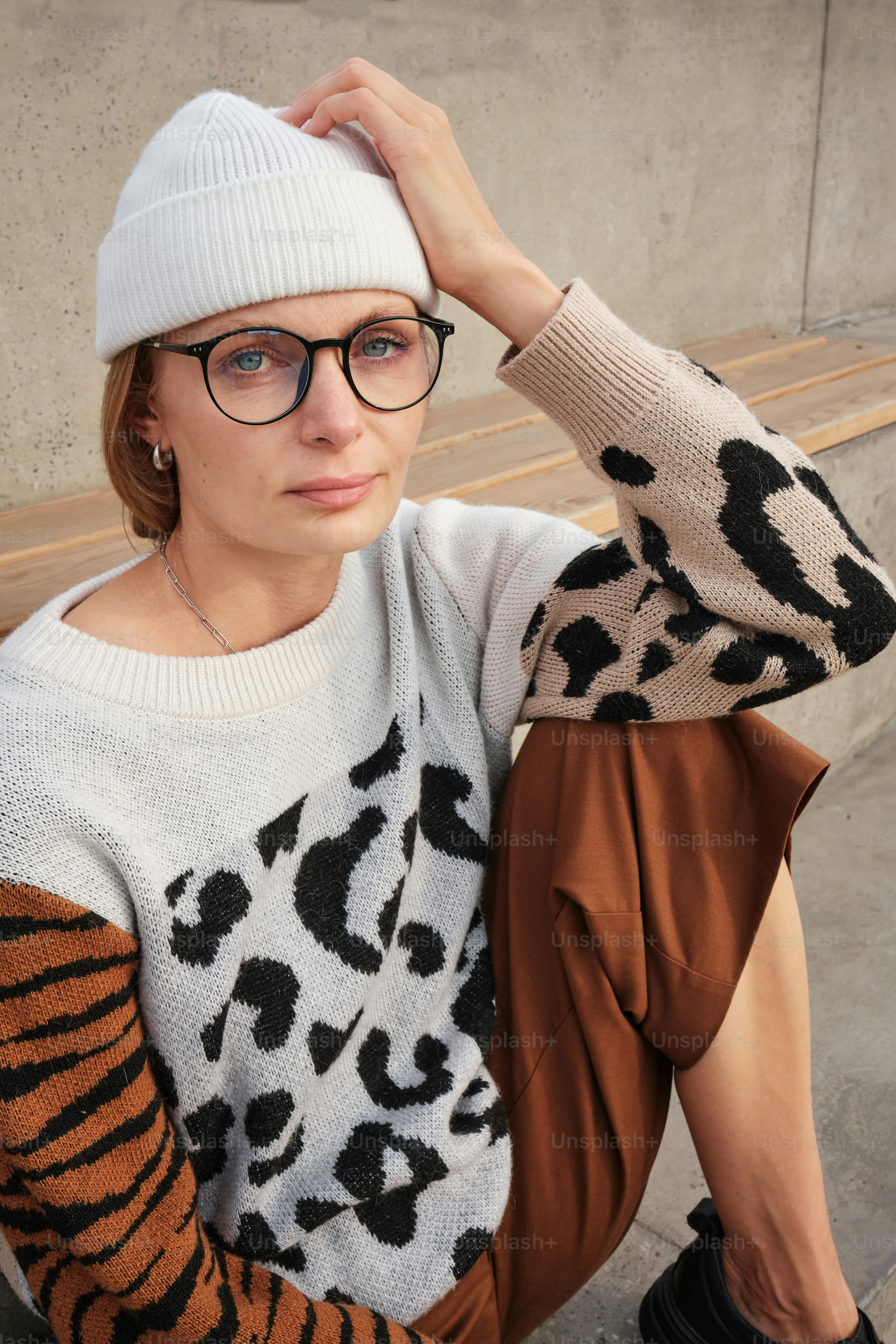 Une femme assise par terre portant des lunettes et un chapeau