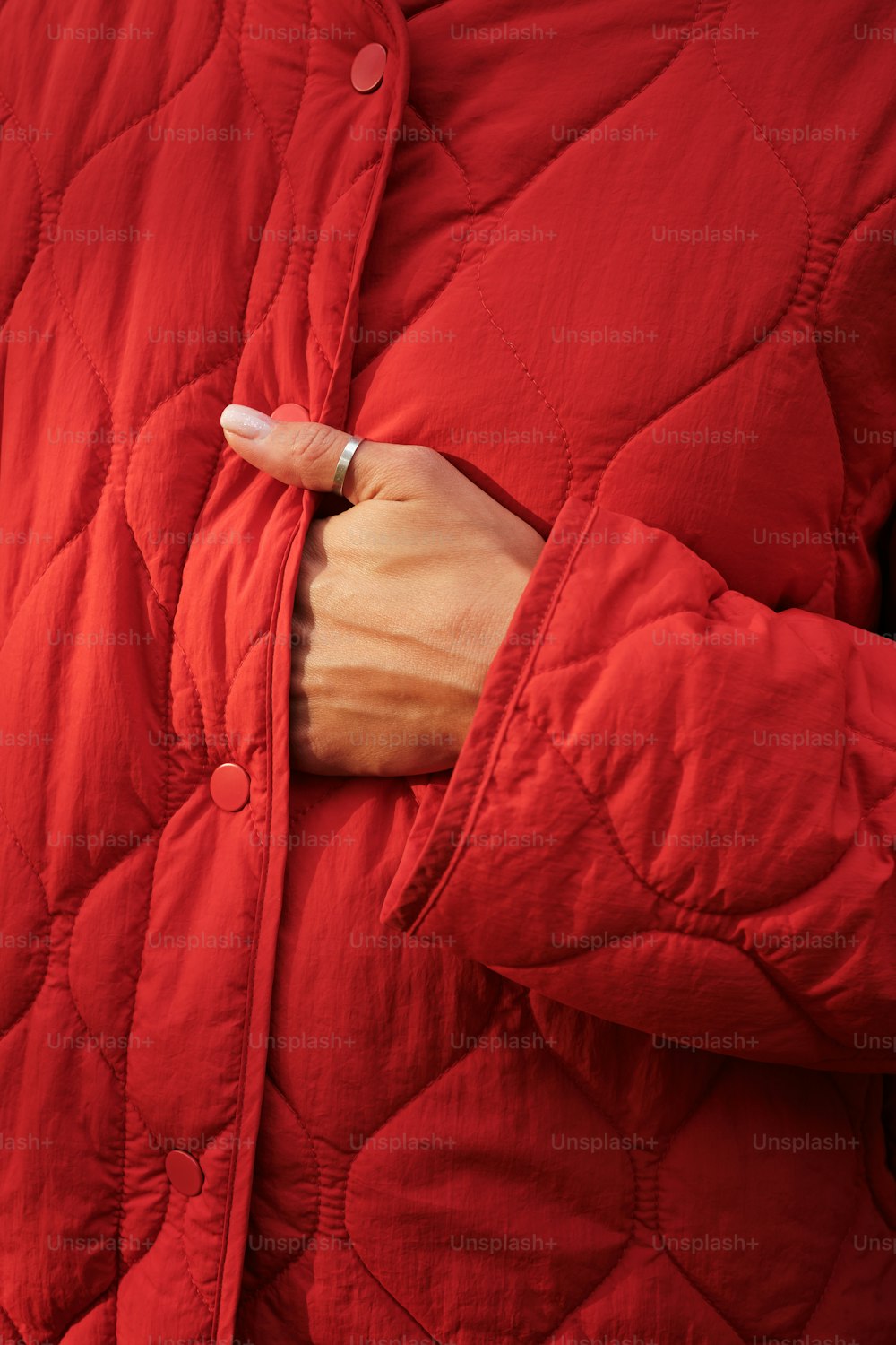 a person wearing a red jacket with a ring on their finger