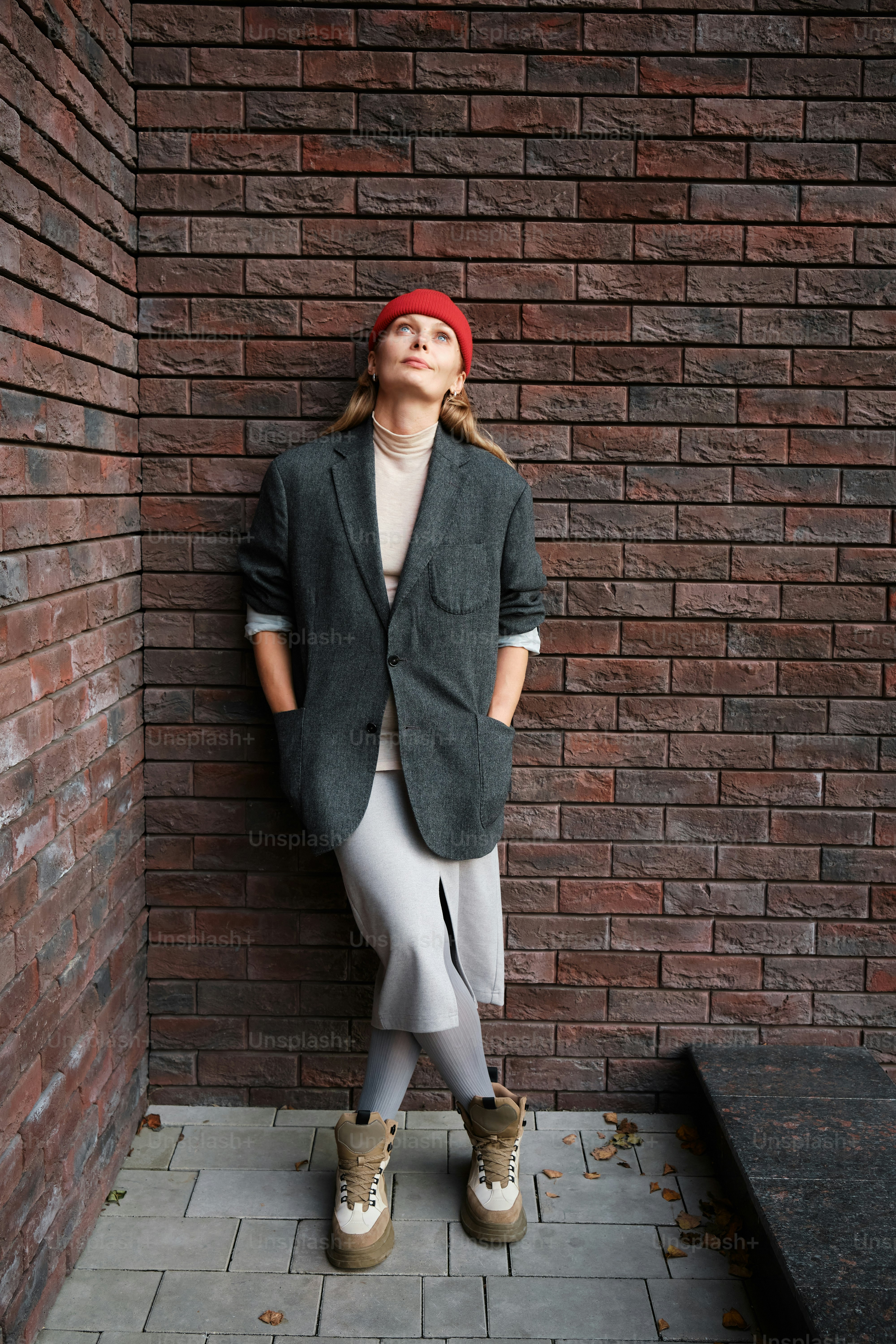 Une femme debout devant un mur de briques