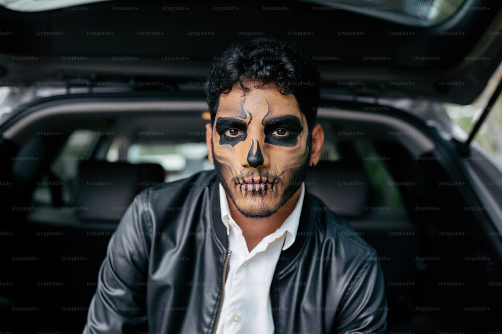 Un hombre con pintura facial sentado en la parte trasera de un automóvil