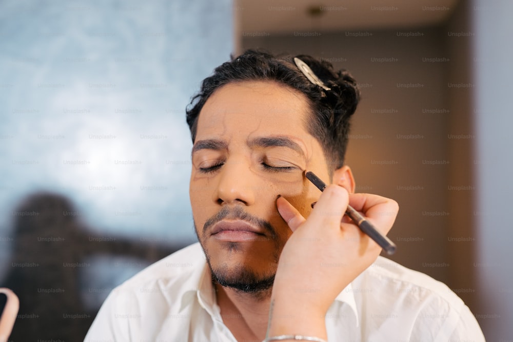 a man getting his make up done with a brush