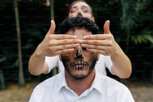 a man with a skull painted on his face covering his eyes