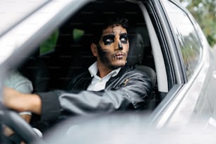 Un homme dans une voiture avec son visage peint comme un squelette