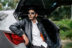 a man in a leather jacket sitting in the trunk of a car