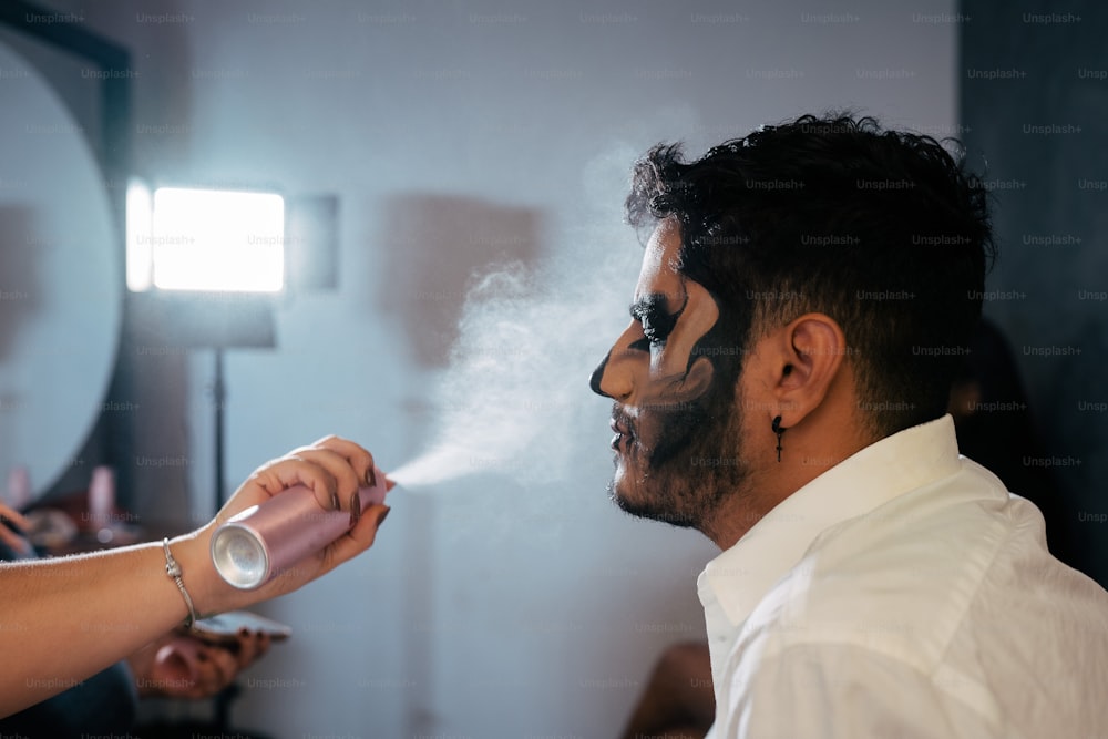 Un uomo con la faccia dipinta fuma una sigaretta