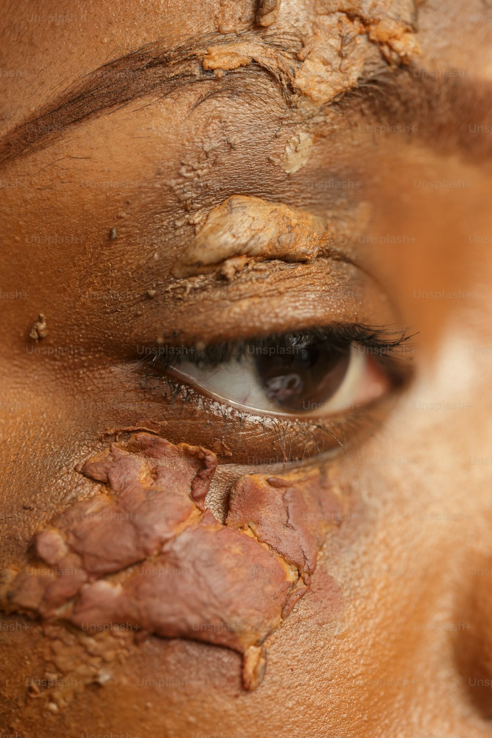 a close up of a woman's face with mud all over her face