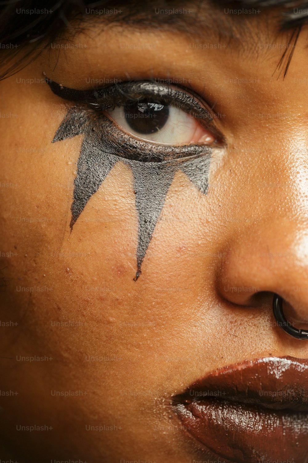 a close up of a woman's face with black and silver makeup