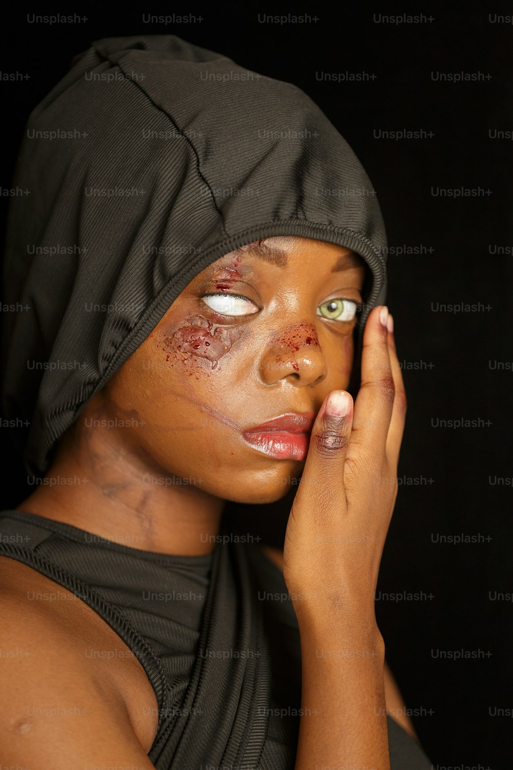 a woman with makeup on her face and a hood over her head