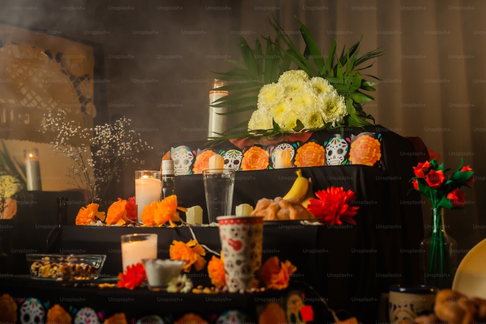 une table avec des bougies, des fleurs et des crânes dessus