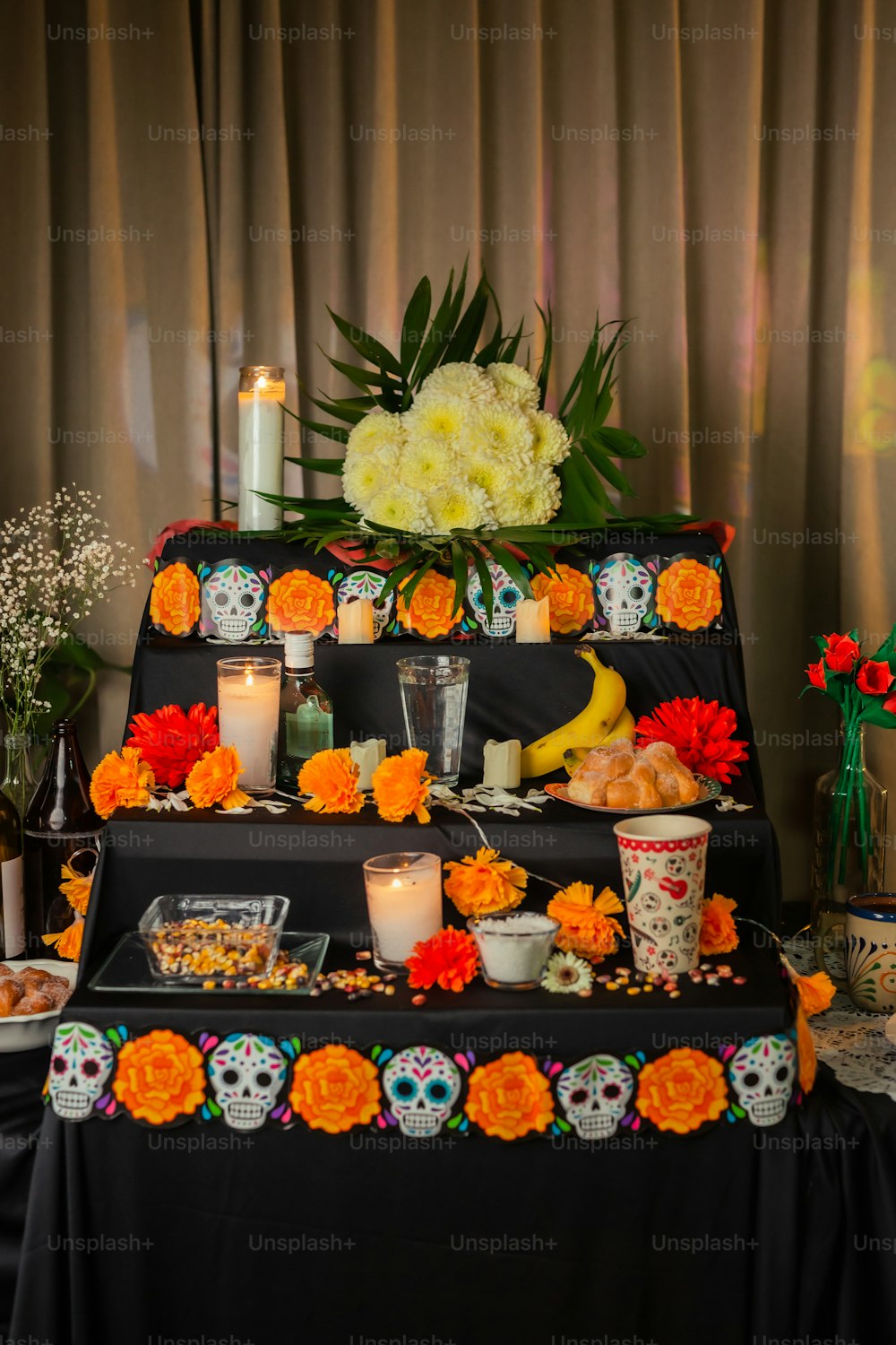 ein Tisch mit Kerzen, Blumen und Totenköpfen darauf
