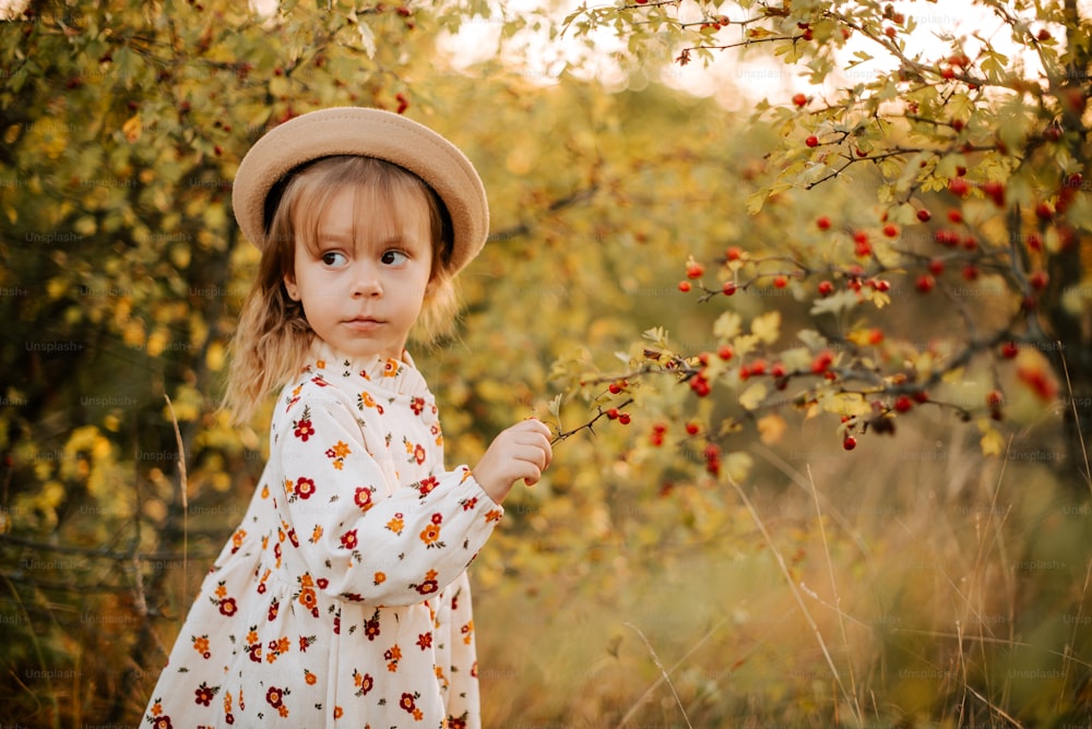 Una niña con un sombrero y sosteniendo una rama