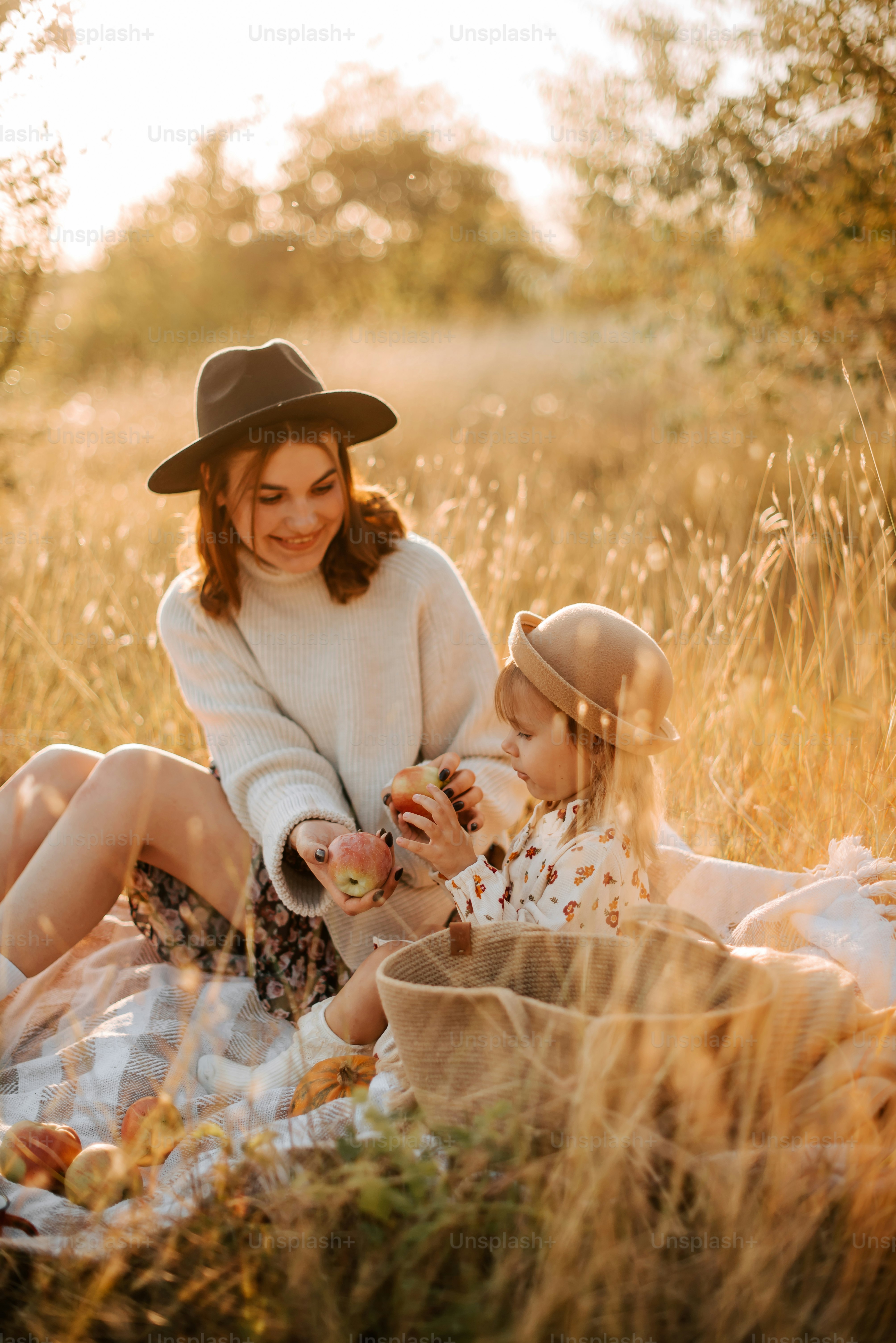 A woman and a child sitting on a blanket in a field photo – Family ...