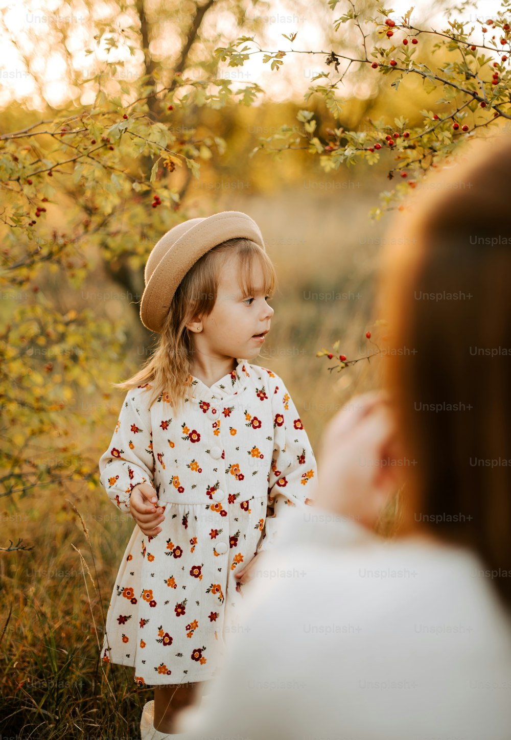 a little girl wearing a hat standing in a field