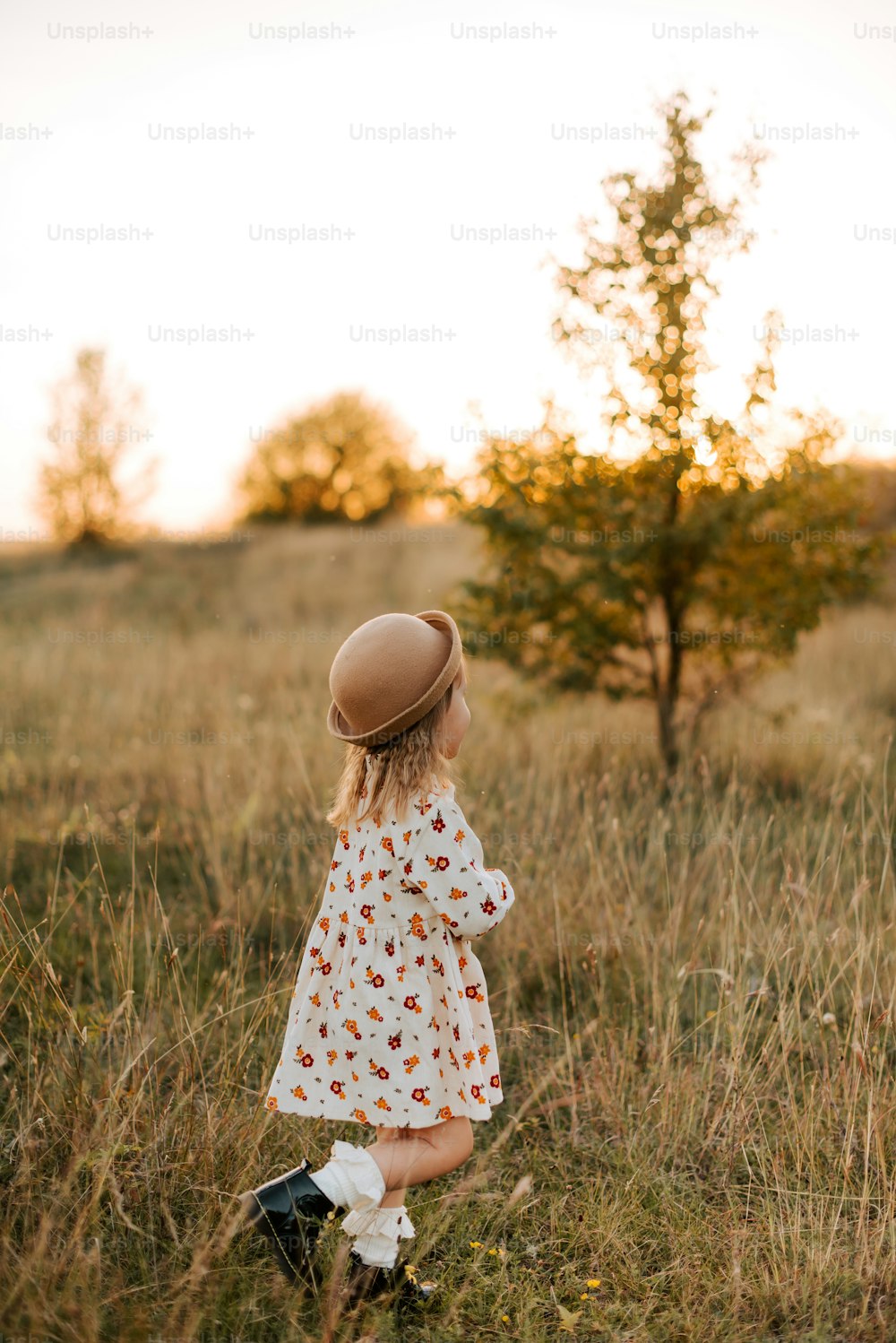 Une petite fille debout dans un champ avec un chapeau