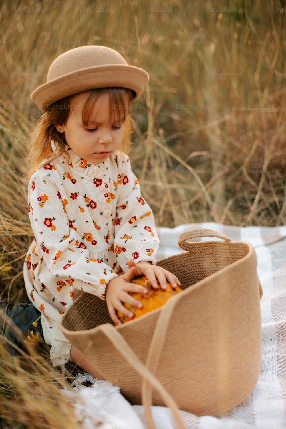 a little girl sitting in a basket on a blanket