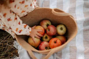 une petite fille tenant un panier plein de pommes