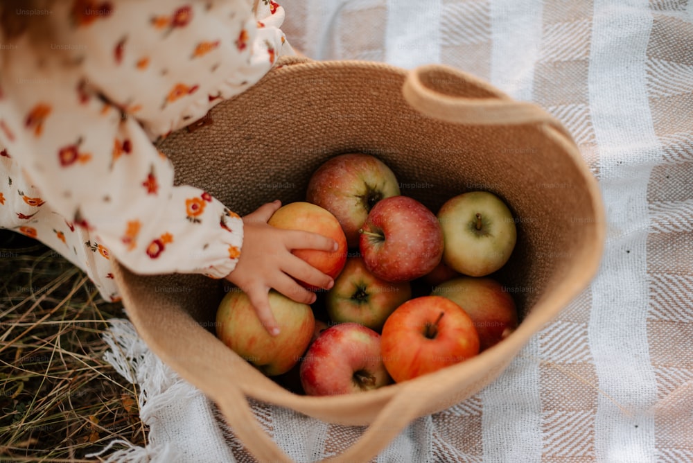 a little girl holding a basket full of apples
