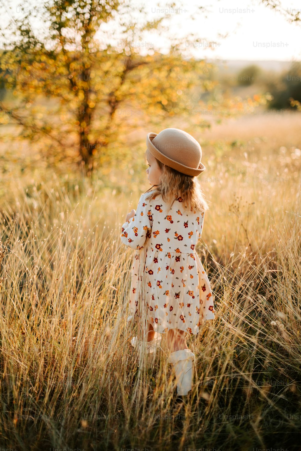 Une petite fille debout dans un champ d’herbes hautes