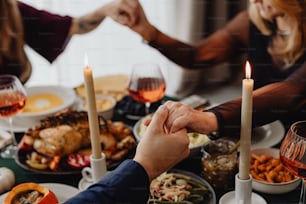 a group of people holding hands over a dinner table