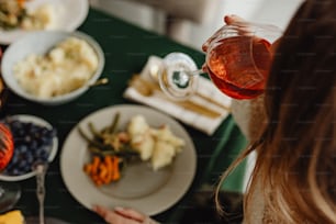 a woman holding a wine glass over a plate of food