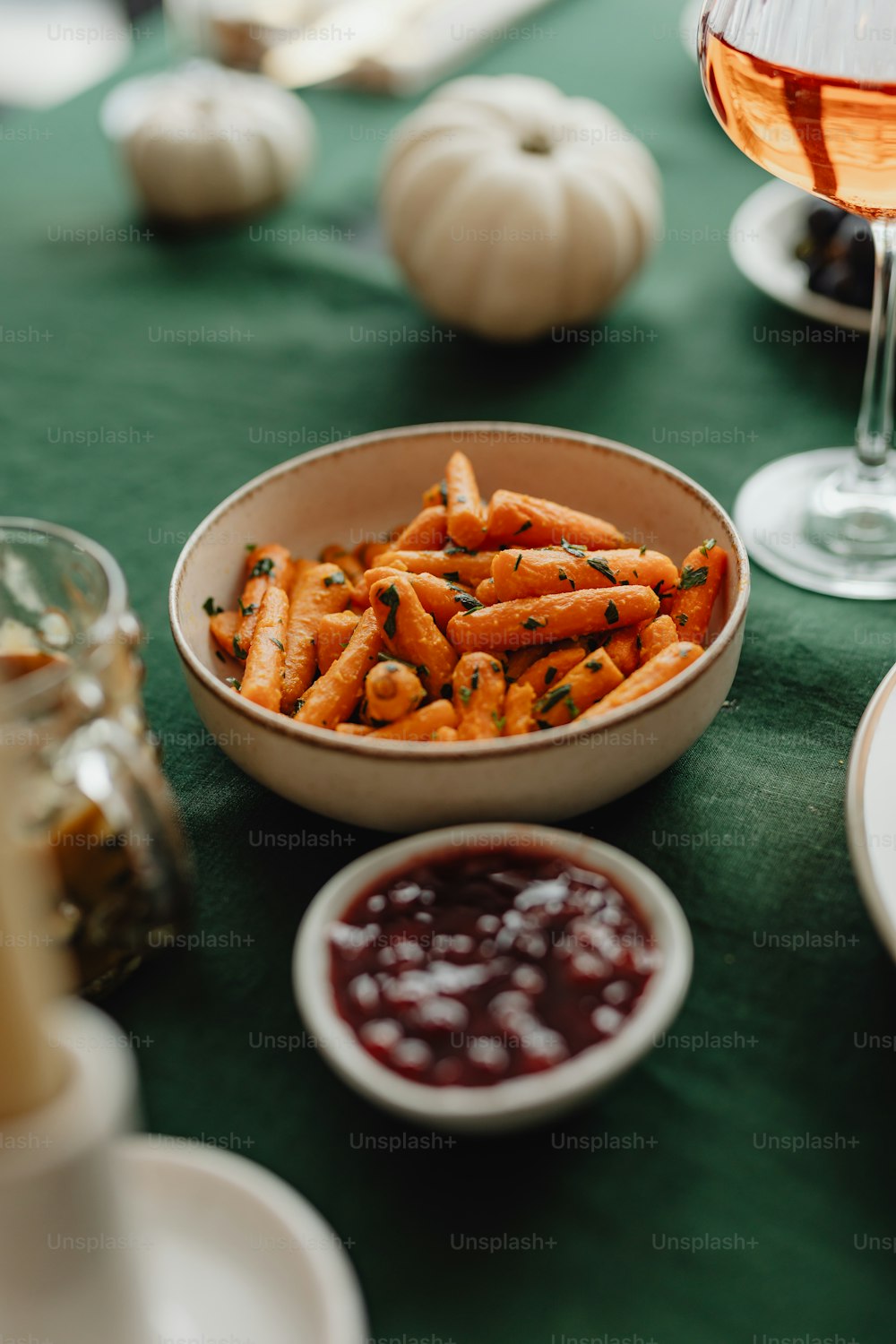 a bowl of carrots next to a glass of wine