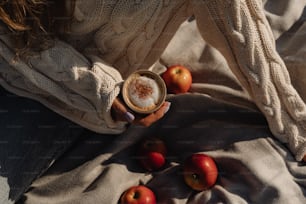 uma mulher segurando uma xícara de café com maçãs ao seu redor