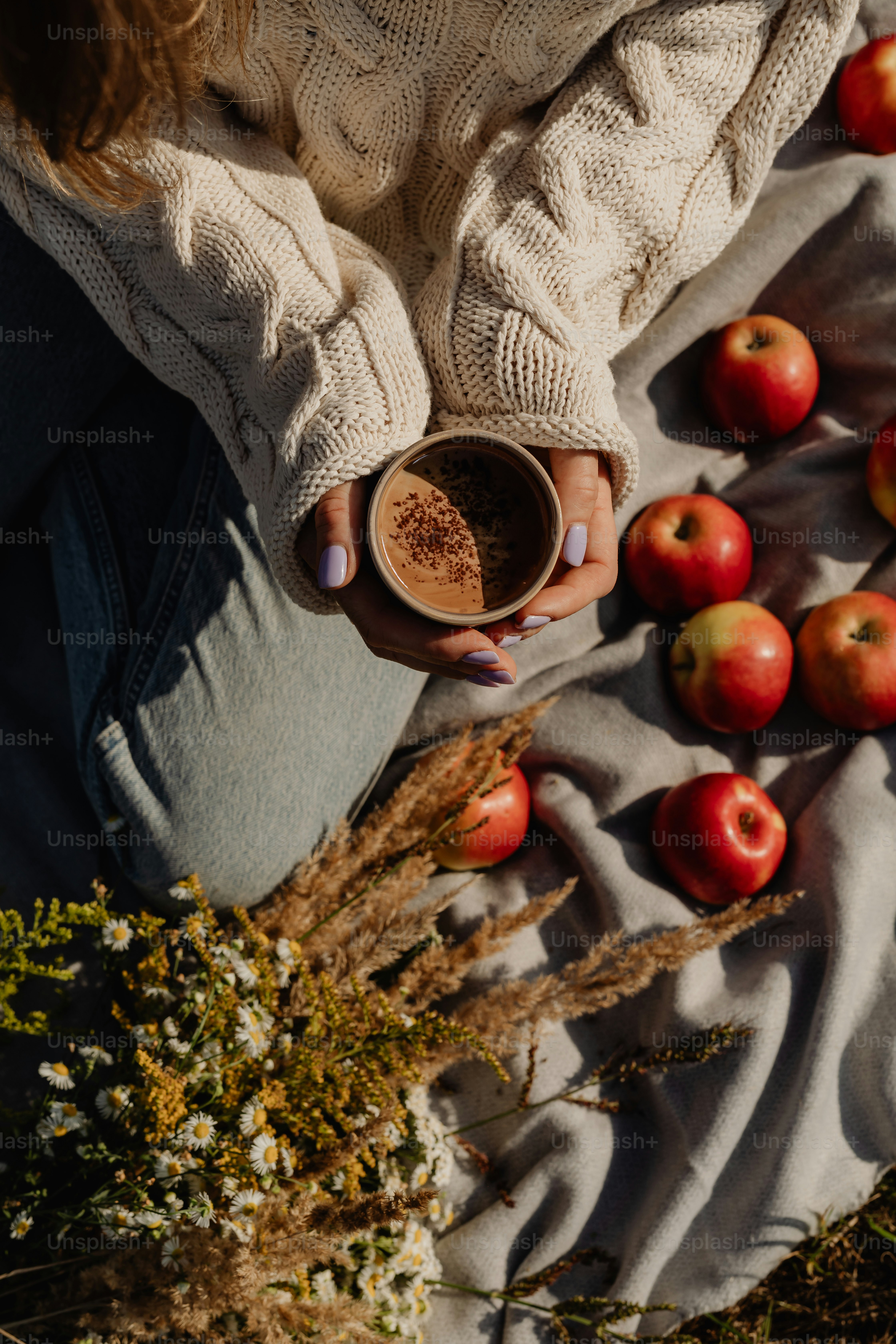 a woman sitting on a blanket holding a cup of coffee