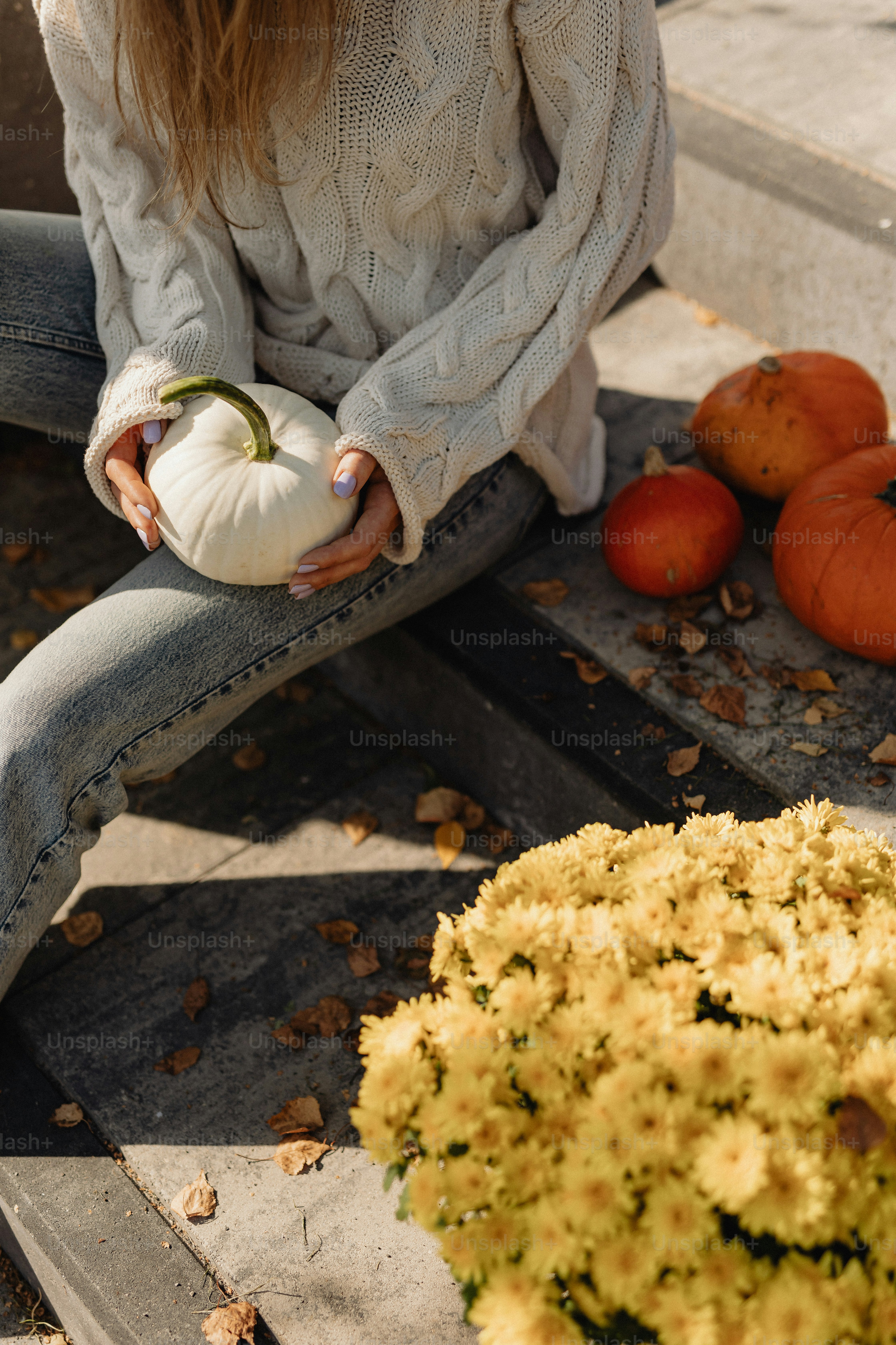 Una donna seduta su un gradino che tiene una zucca