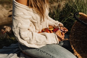 a woman sitting on the ground with a basket of fruit