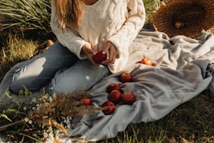 사과를 땅에 대고 담요 위에 앉아 있는 여자