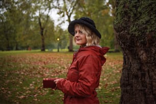 a woman standing next to a tree in a park