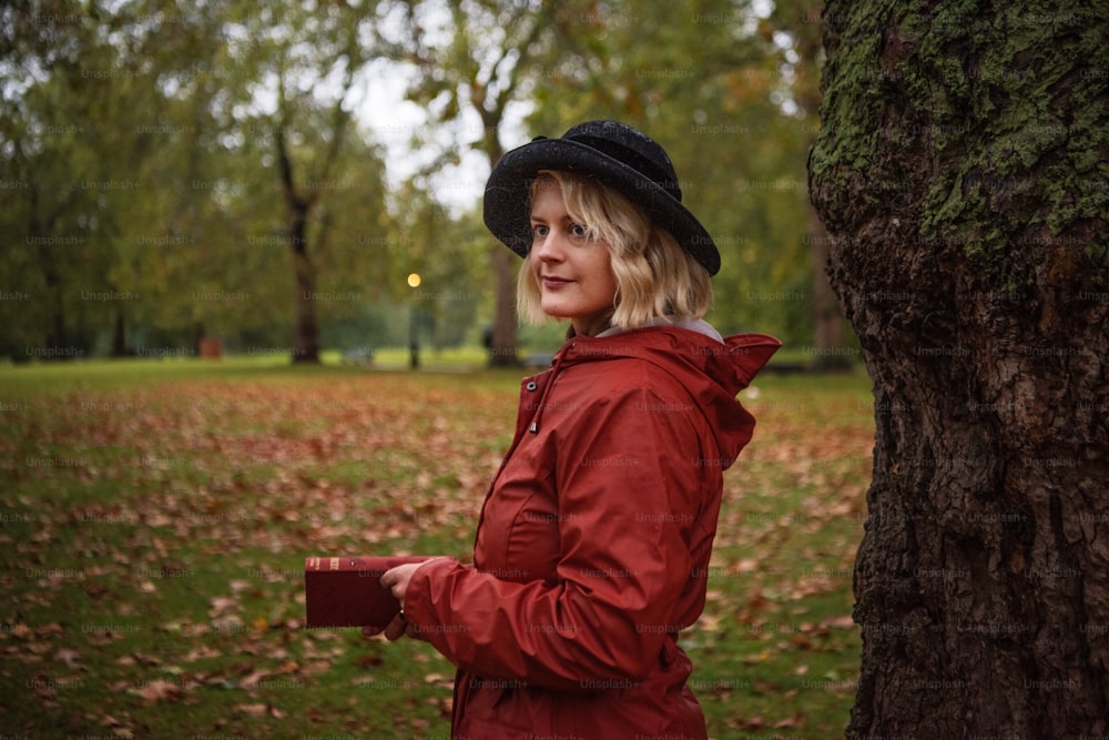 a woman standing next to a tree in a park