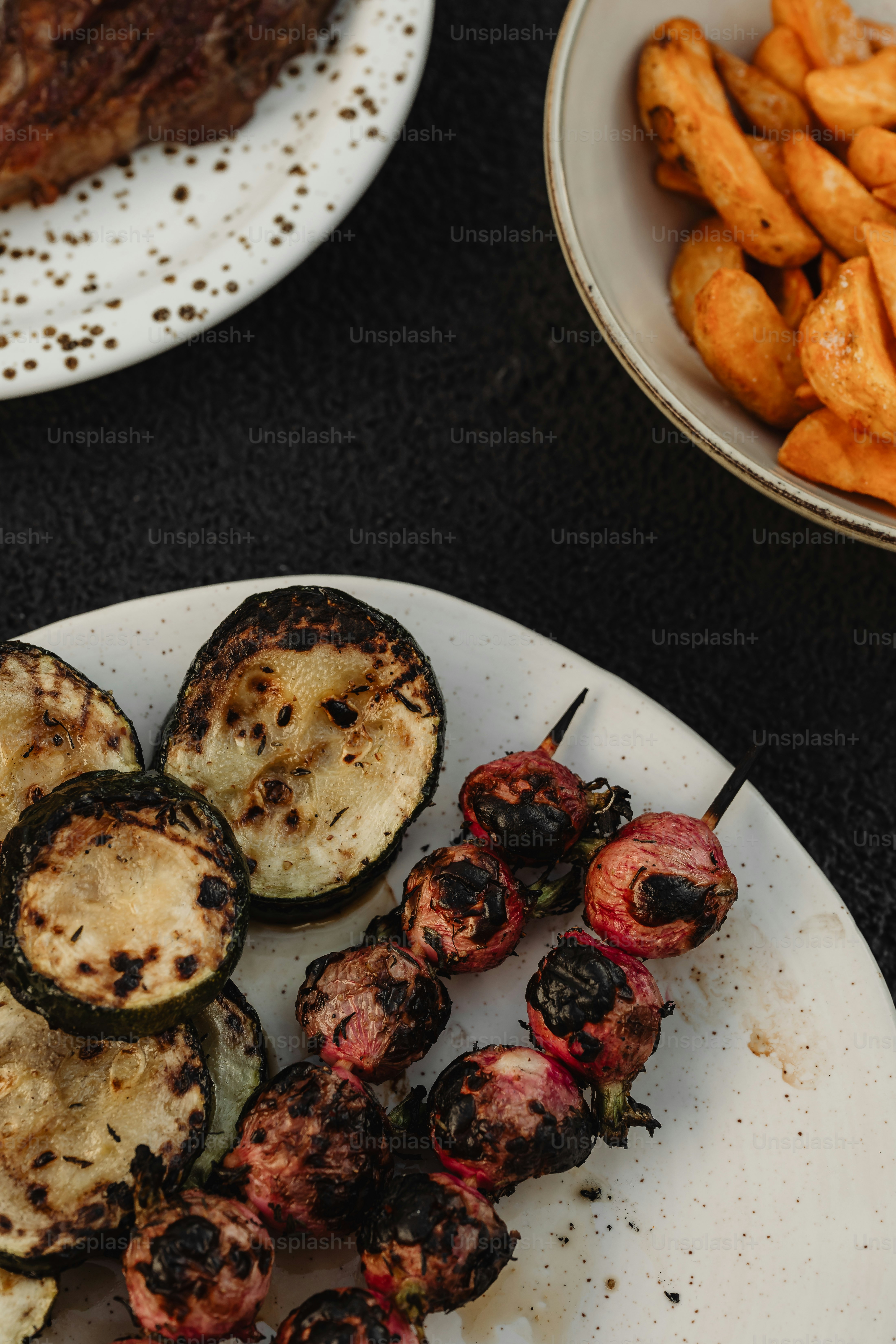 un plato blanco cubierto con verduras a la parrilla y carne