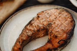 un pezzo di pesce alla griglia su un piatto bianco